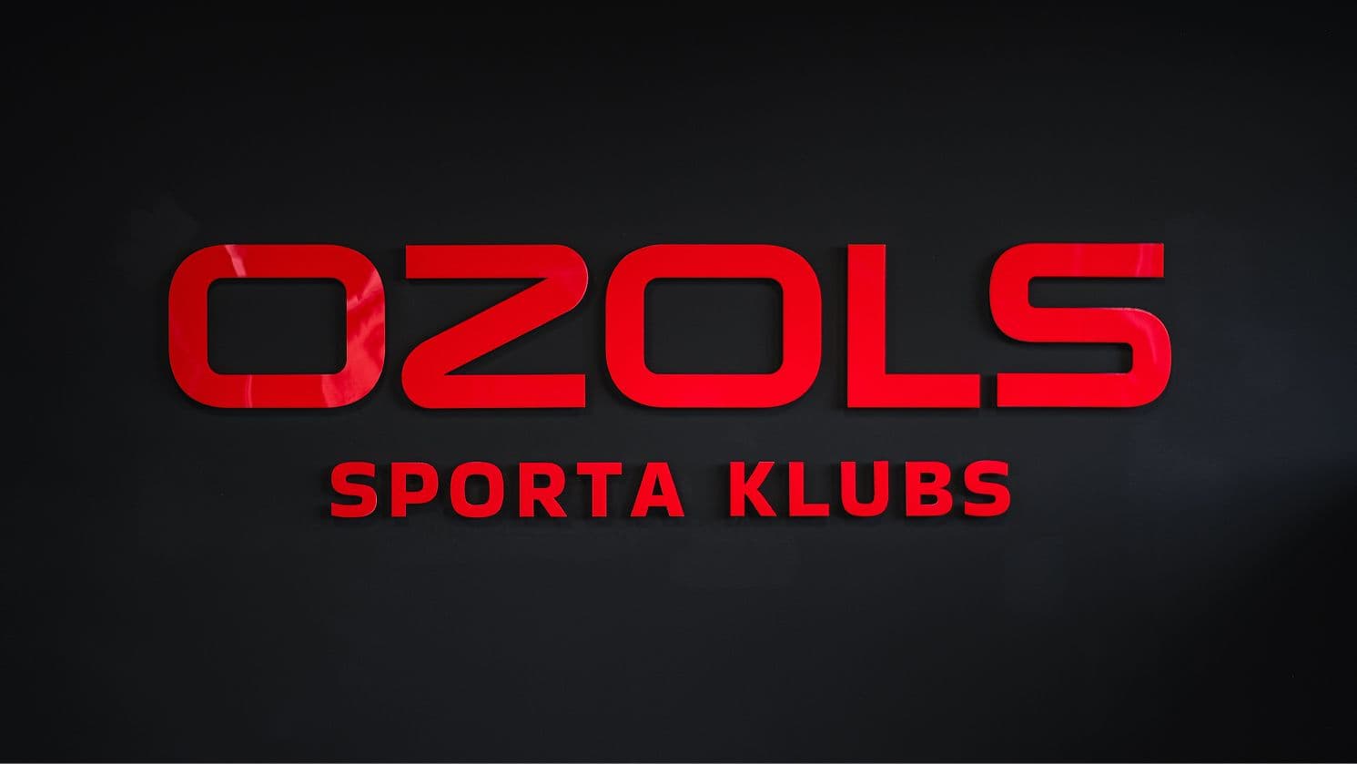 Gaiši sarkans Ozols sporta kluba zīmols uz melna fona